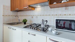 A kitchen with white cabinets, a gas stove, a microwave, and a sink. - Porto Letizia Mascagni 5, Porlezza, Italy (Porlezza)