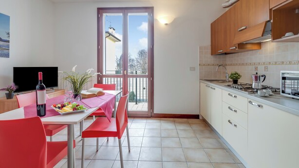 A modern kitchen with a dining area, a TV, and a balcony with a view. - Porto Letizia Mascagni 5, Porlezza, Italy (Porlezza)