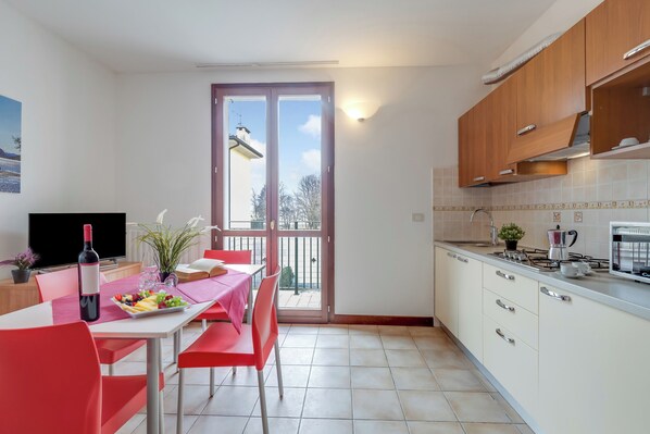 Une cuisine moderne avec un coin repas, un téléviseur et un balcon offrant une vue agréable.