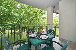 A balcony with a table set for two, featuring a fruit basket, a vase with flowers, and a basket of bread. - Porto Letizia Venezia 6, Porlezza, Italy (Porlezza)