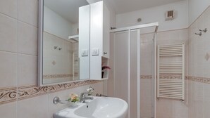 A bathroom with a white sink, a mirror, and a shower enclosure. - Porto Letizia Venezia 5, Porlezza, Italy (Porlezza)
