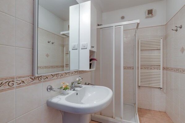 Une salle de bain avec un lavabo blanc, un miroir et un espace douche.