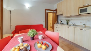 A modern kitchen with wooden cabinets, a microwave, and a dining area with a red table and chairs. - Porto Letizia Venezia 5, Porlezza, Italy (Porlezza)