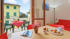 A balcony with a table, chairs, a potted plant, and a table with food and drinks. - Porto Letizia Venezia 5, Porlezza, Italy (Porlezza)