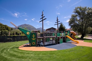 Ein Spielplatz mit Rutsche, Klettergerüsten und einem Spielbereich im Schiffsdesign.