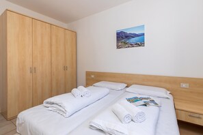 Ein Hotelzimmer mit zwei Einzelbetten, einem Holzschrank und einem gerahmten Bild an der Wand.