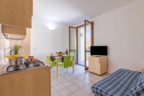 Ein kompakter Wohnbereich mit Küchenzeile, Essplatz und Bett.