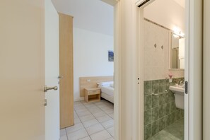 Une chambre d’hôtel comprenant un lit, une table de chevet et une salle de bain avec un lavabo et un miroir.