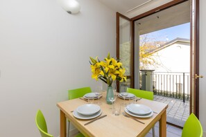 A dining table set with plates, cutlery, and a vase of yellow flowers.