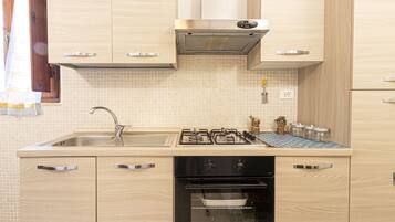 A kitchen with a sink, stove, oven, and wooden cabinets.