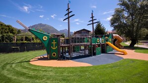 Une aire de jeux avec un toboggan, des structures d’escalade et un espace de jeux sur le thème des bateaux.