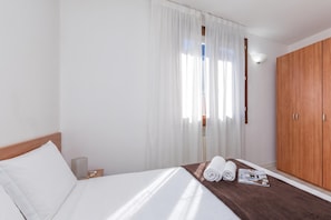 A hotel room with a bed, a wooden wardrobe, and a window with sheer curtains. - Porto Letizia Leoncavallo 10, Porlezza, Italy (Porlezza)
