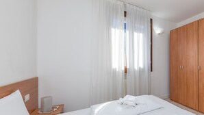 Une chambre d’hôtel avec un lit bien fait, une table de chevet en bois avec une lampe et une armoire.