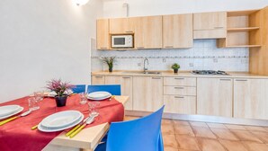 A modern kitchen with wooden cabinets, a microwave, and a tiled backsplash. - Porto Letizia Bologna 4, Porlezza, Italy (Porlezza)
