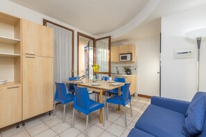 A compact kitchen with a dining area, a microwave, and a sofa.