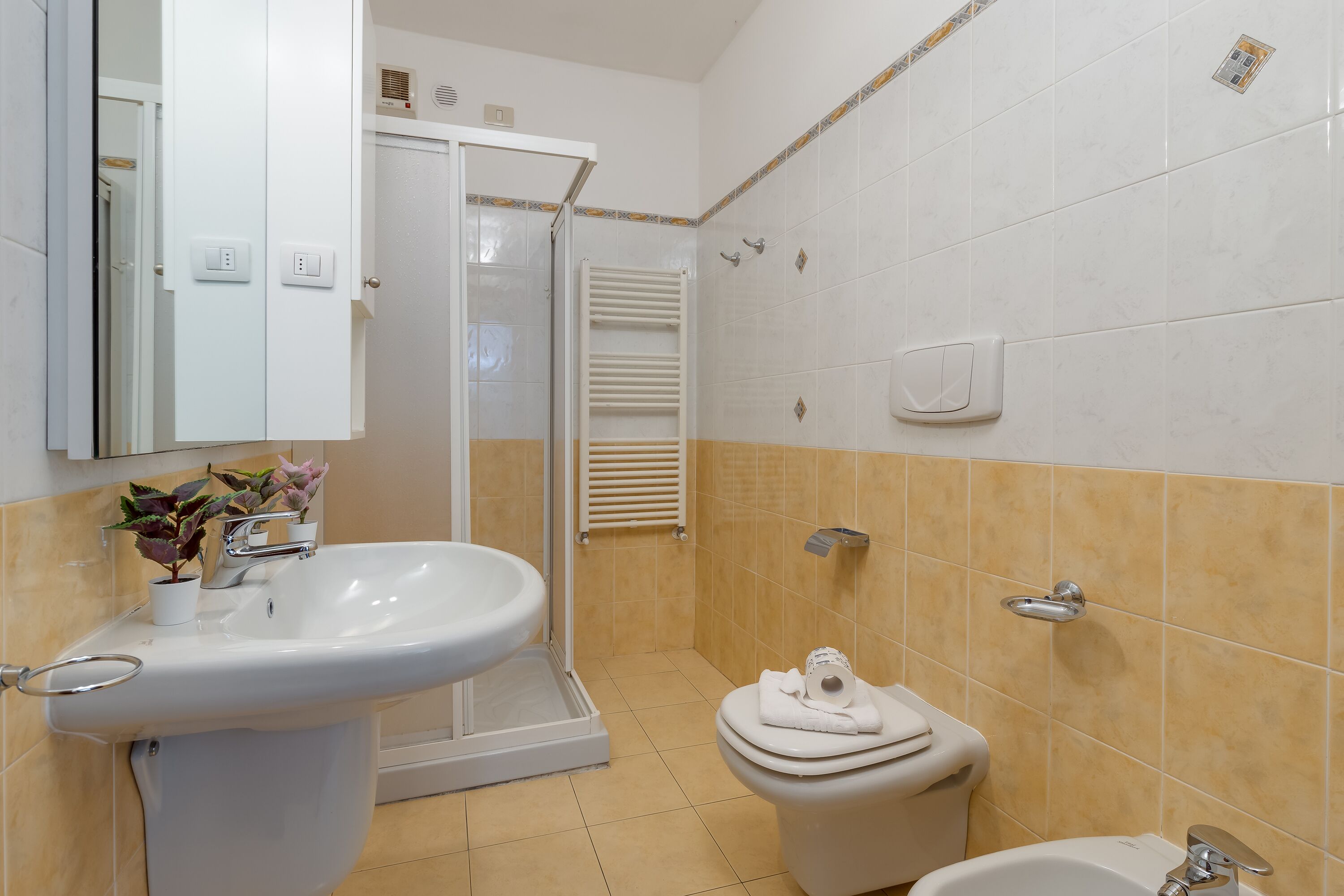 Et badeværelse med vask, toilet og bruser.