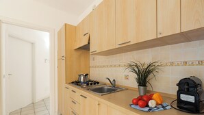 Une cuisine avec des meubles en bois, un évier en acier inoxydable, une cuisinière à gaz et une machine à café.