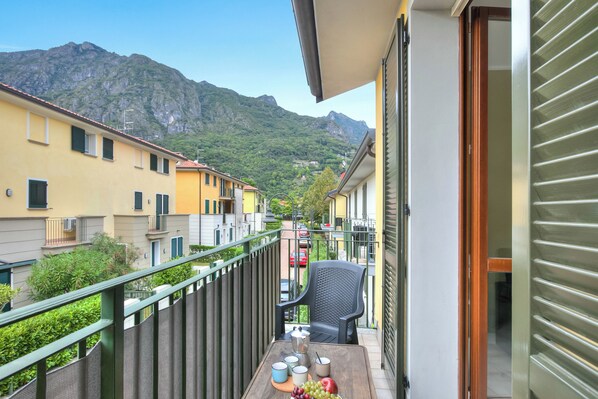 A balcony with a table set for two, overlooking a mountain and residential buildings.