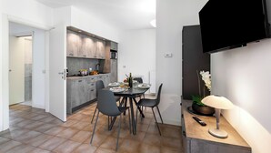 A modern kitchen with grey cabinets, a dining table with four chairs, and a flat-screen TV mounted on the wall. - Porto Letizia Ferrara 3, Porlezza, Italy (Porlezza)