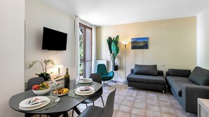 A modern living room with a dining area, a flat-screen TV mounted on the wall, a green chair, a grey sofa, and a lamp. - Porto Letizia Ferrara 3, Porlezza, Italy (Porlezza)