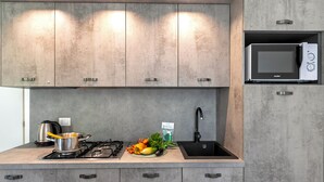 A modern kitchen with grey cabinets, a built-in microwave, a gas stove, and a sink. - Porto Letizia Ferrara 3, Porlezza, Italy (Porlezza)