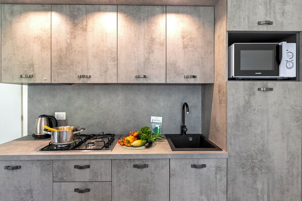 A modern kitchen with grey cabinets, a built-in microwave, a gas stove, and a sink.