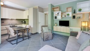 En moderne stue med sofa, spisebord og fjernsyn.