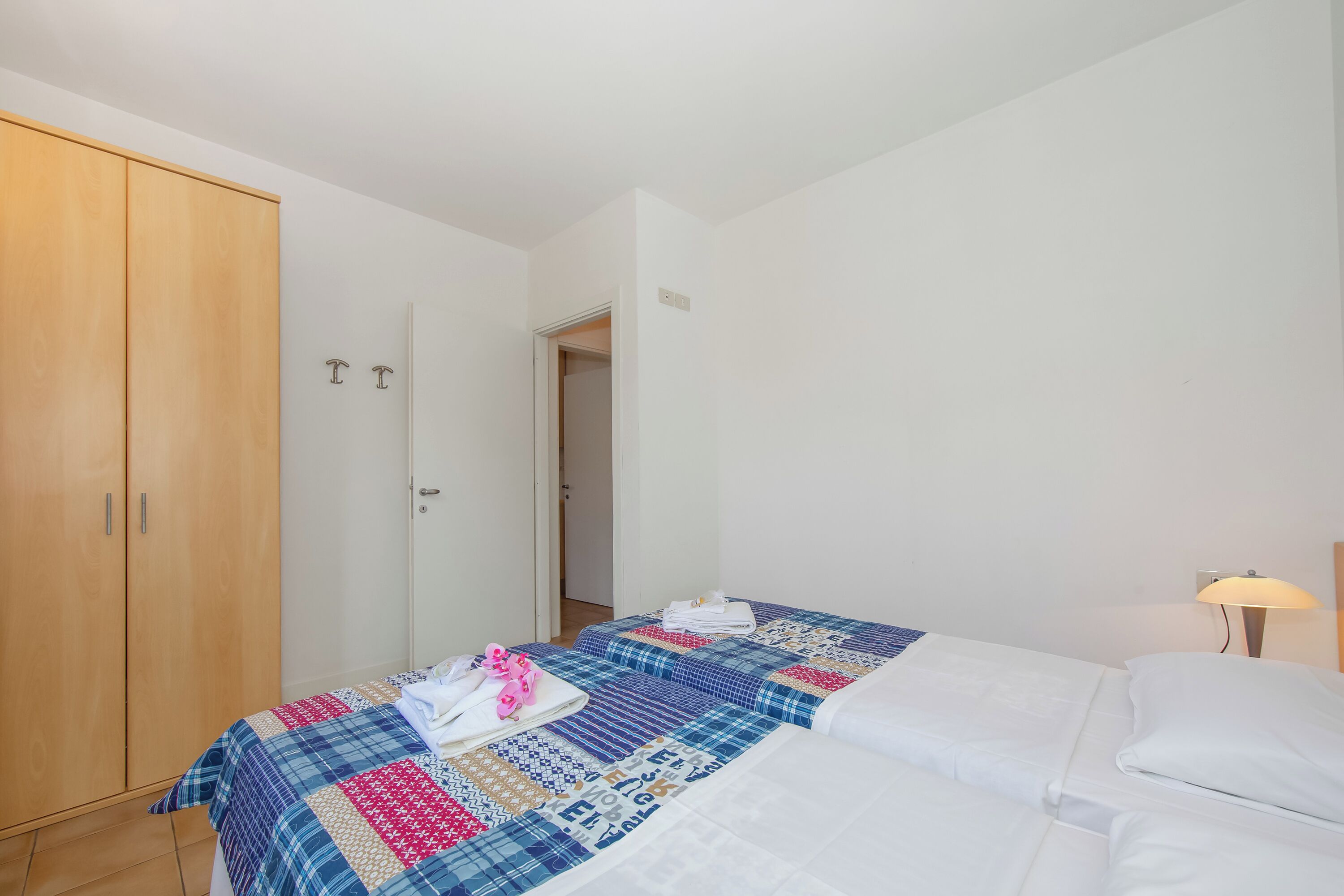 Een slaapkamer met een bed, een kledingkast en een nachtkastje met een lamp.