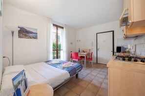 Une chambre avec un lit, un bureau et une kitchenette.