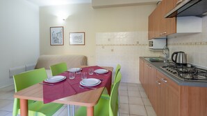 A compact kitchen with a dining table set for four, equipped with a gas stove and a kettle. - Porto Letizia Leoncavallo 2, Porlezza, Italy (Porlezza)