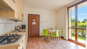 Una cocina con estufa a gas, un lavamanos y un comedor con mesa y sillas.