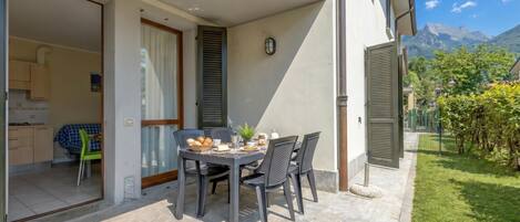 A patio with a table set for breakfast, a kitchen visible through an open door, and a mountain view in the background.