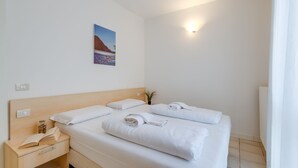 Een hotelkamer met een groot bed, een nachtkastje met een boek en een lamp, en een aan de muur hangend schilderij.