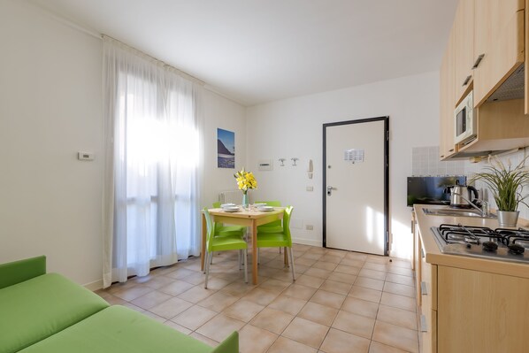 Eine kleine Küche mit Essbereich, einem grünen Sofa und einer weißen Tür.