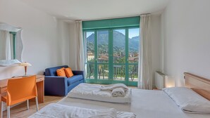 A hotel room with two beds, a desk, a chair, and a view of mountains. - Porto Letizia T5, Porlezza, Italy (Porlezza)