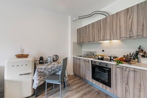 A compact kitchen with wooden cabinets, a white countertop, and a vintage white refrigerator.