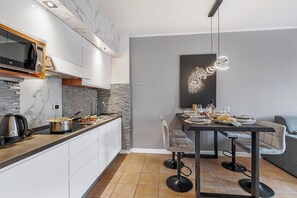 A modern kitchen with a marble backsplash, a built-in microwave, and a stone accent wall.
