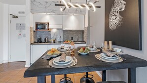 Een moderne keuken met een marmeren spatwand, een eettafel gedekt voor zes personen met borden, glazen en een fles wijn.