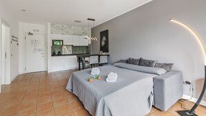 Een moderne hotelkamer met een groot bed, een slaapbank, een kitchenette en een badkamer.