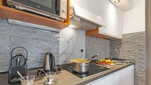 Een moderne keuken met een ingebouwde magnetron, waterkoker en fornuis.