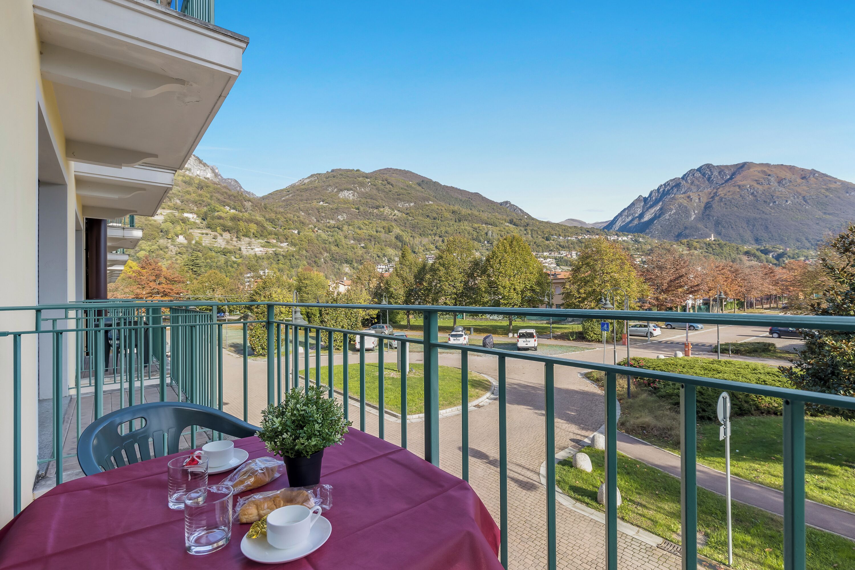 A balcony with a table set for two, overlooking a mountain and a road.