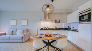 A modern kitchen with a dining area, featuring a central island, white cabinetry, and a contemporary pendant light. - Porto Letizia P18, Porlezza, Italy (Porlezza)
