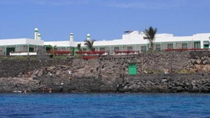 Un bâtiment situé sur la côte, avec un rivage rocheux et un ciel bleu dégagé.