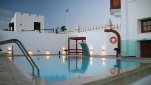 Une piscine avec une échelle en métal, une table en bois et une bouée de sauvetage fixée au mur.