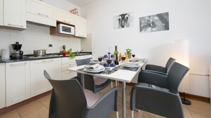 Une cuisine moderne avec des meubles blancs, un four à micro-ondes et un coin repas avec une table dressée pour quatre personnes.