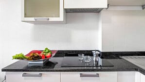 Une cuisine moderne avec un plan de travail noir, des armoires blanches et un évier en acier inoxydable.