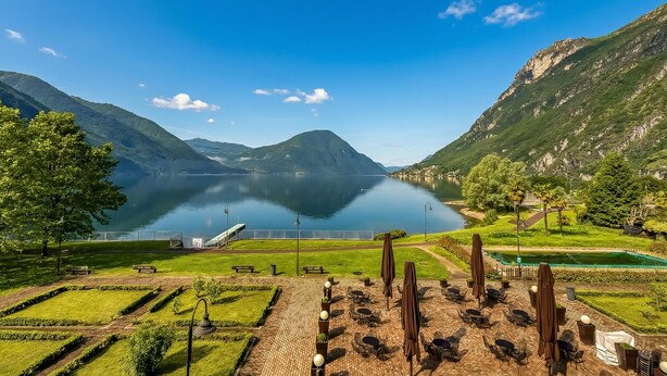 A lakeside view with a patio area, benches, and a gazebo.