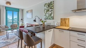 A modern kitchen with a dining area, a view of the outdoors, and a large window with curtains.
