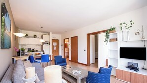 A modern living room with a grey sofa, blue chairs, a coffee table, and a TV on a wooden cabinet. - Porto Letizia S3 B1, Porlezza, Italy (Porlezza)