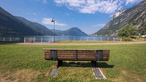 Een bankje in een park, met een meer en bergen op de achtergrond.
